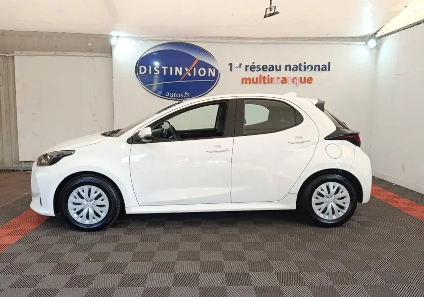 Toyota Yaris hybride blanche vue de profil côté gauche, avec jantes standard et spoiler arrière noir.