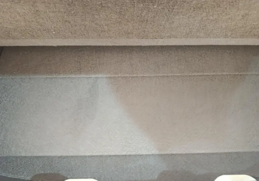 Vue arrière en léger contre-plongée d'une Toyota Yaris hybride blanche, avec spoiler de coffre visible.