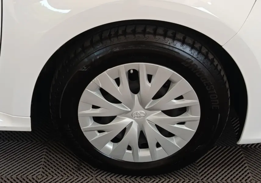 Gros plan sur la roue arrière droite blanche d’une Toyota Yaris hybride 2022 avec enjoliveur argenté à motifs dynamiques.