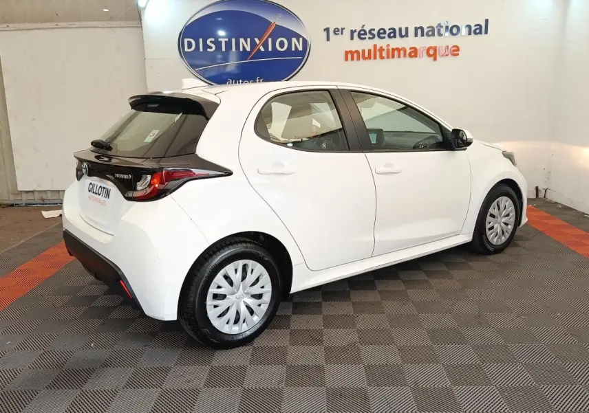 Toyota Yaris hybride blanche vue en 3/4 arrière droit, avec toit noir et jantes à enjoliveurs.