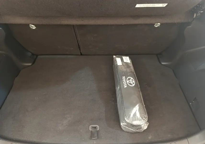 Coffre arrière de Toyota Yaris hybride blanche 2022, vue intérieure montrant la banquette rabattue et une housse Toyota.