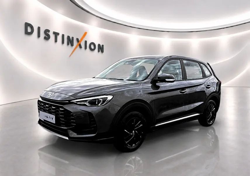 MG ZS 1.5 hybrid Camden grey en 3/4 avant droit, avec jantes noires et calandre marquée dans un showroom lumineux.