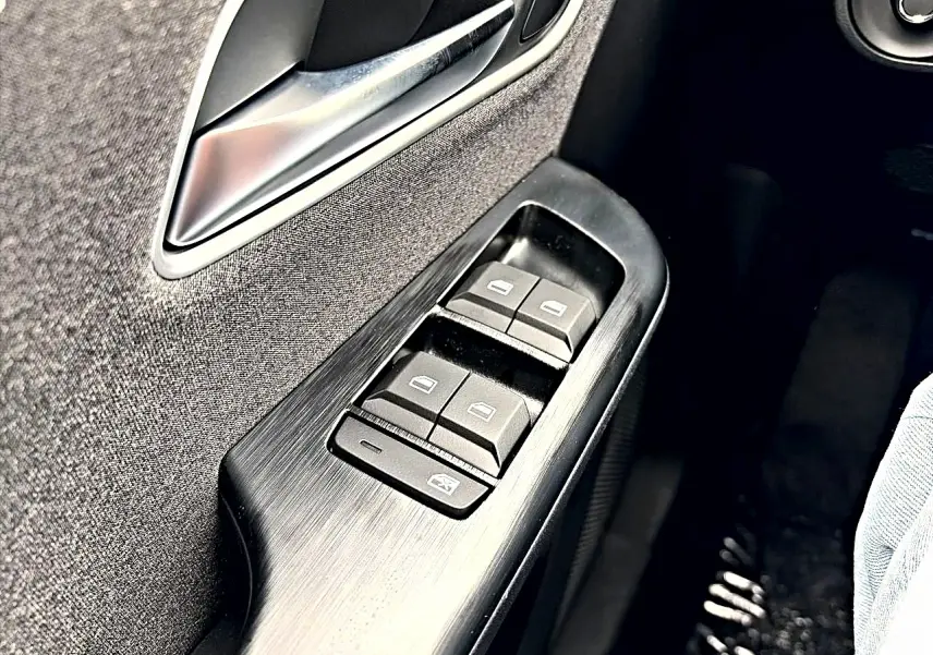 Gros plan sur les commandes des vitres électriques côté gauche de la porte avant d'un MG ZS 1.5 hybrid Camden grey.