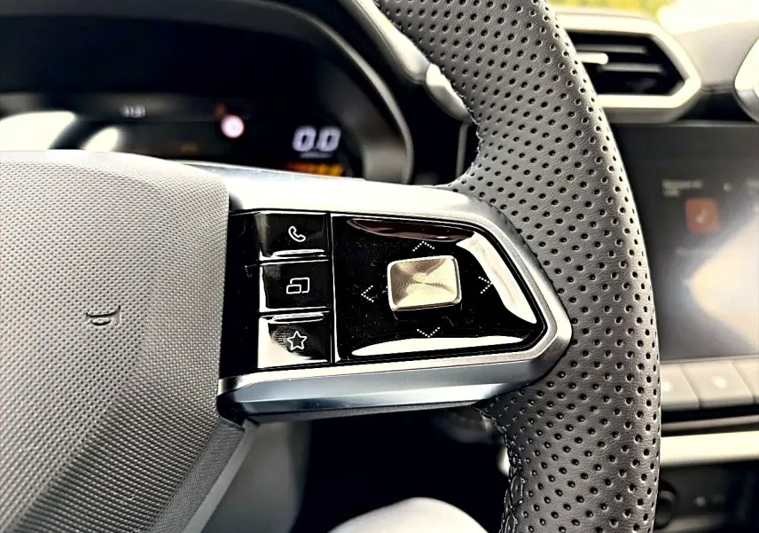 Gros plan sur la partie gauche du volant perforé noir du MG ZS 1.5 hybrid 2026 avec commandes multifonctions.