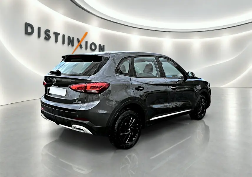 Vue 3/4 arrière droite du MG ZS Camden grey 2026 avec jantes noires et becquet arrière dans un showroom.