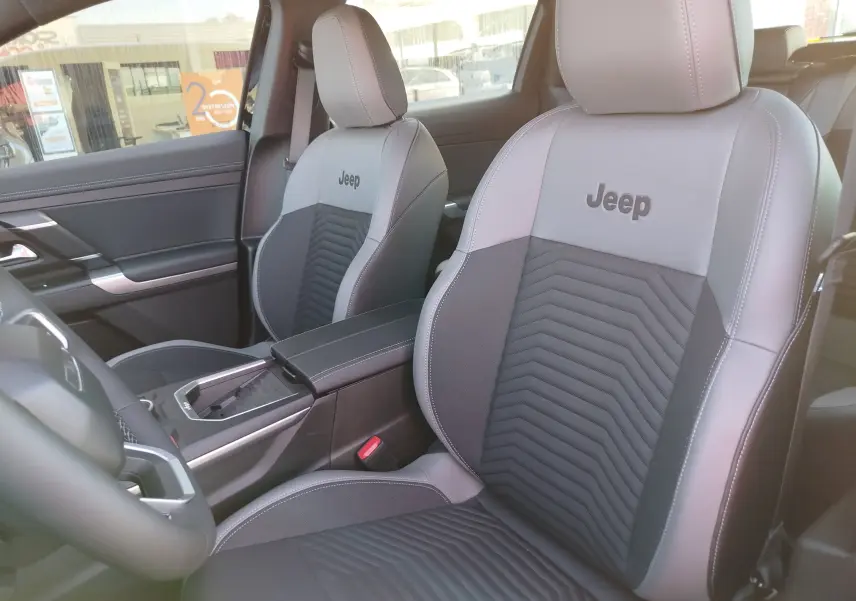 Vue intérieure rapprochée des sièges avant en cuir gris clair et foncé avec logo Jeep brodé sur les appuie-têtes.