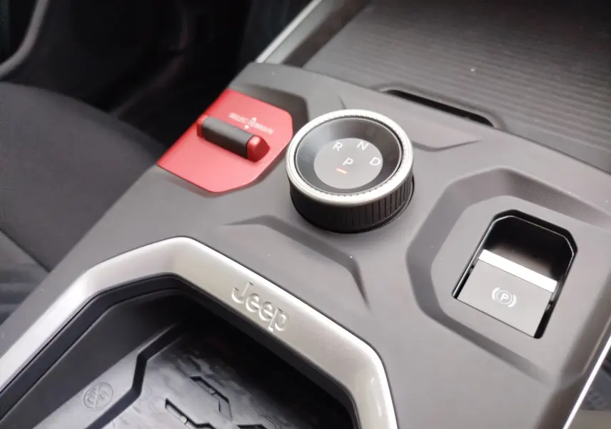 Gros plan sur la console centrale du Jeep Compass noir Vulcano, avec molette de boîte auto et bouton frein électrique.