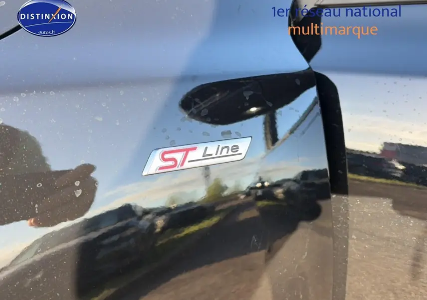 Gros plan sur l'emblème ST-Line sur la porte noire brillante d'une Ford Focus 2024, reflet extérieur visible.