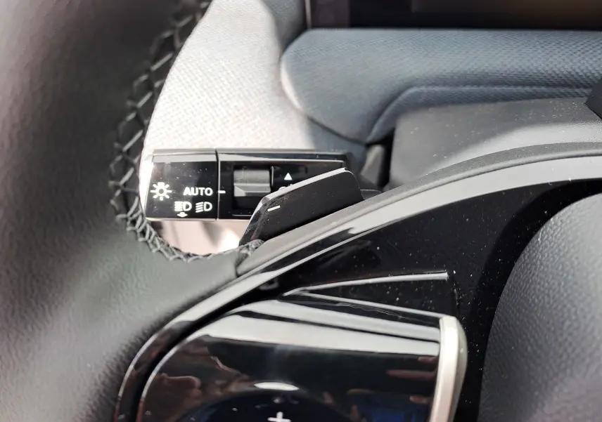 Gros plan sur la commande d’éclairage et la palette de changement de vitesse noire dans l’habitacle gris du Citroën C5 Aircross.