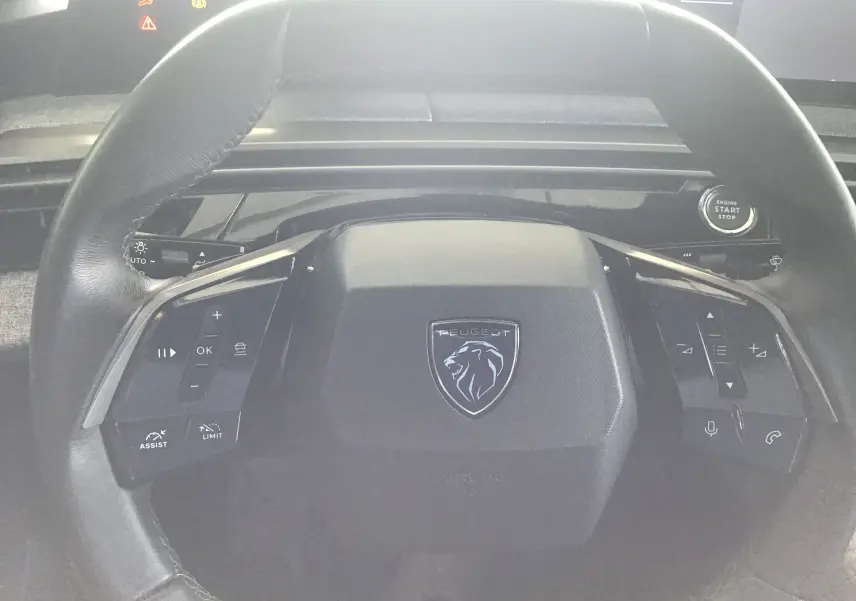 Vue rapprochée du volant cuir noir du Peugeot 3008 gris titane 2026, avec commandes multifonctions et bouton start/stop.
