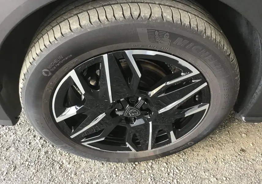 Gros plan sur la jante noire et argentée de 19 pouces d'un Peugeot 3008 gris titane, avec pneu Michelin visible.