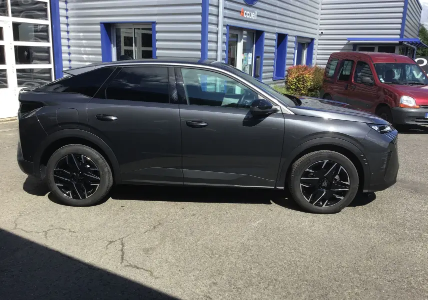 Peugeot 3008 gris titane vue de profil côté gauche, avec jantes noires et vitres teintées, stationné devant un bâtiment.