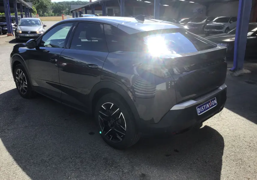 Peugeot 3008 gris titane en 3/4 arrière droit, avec jantes noires et vitres teintées, sous un fort éclairage solaire.