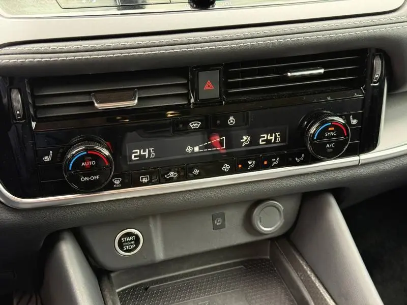 Gros plan sur la console centrale du Nissan Qashqai 2025, avec commandes climatisation bi-zone et bouton start/stop.