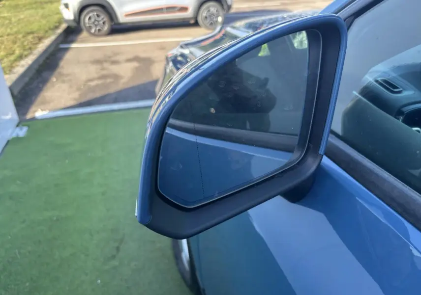 Rétroviseur extérieur droit bleu Fjord Blue d'un Volvo XC40 2024, avec partie de la portière visible.