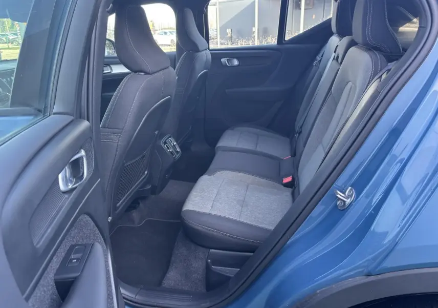 Vue côté gauche de l’arrière du Volvo XC40 Fjord Blue avec sièges bi-matière gris et noir et aérateurs centraux.