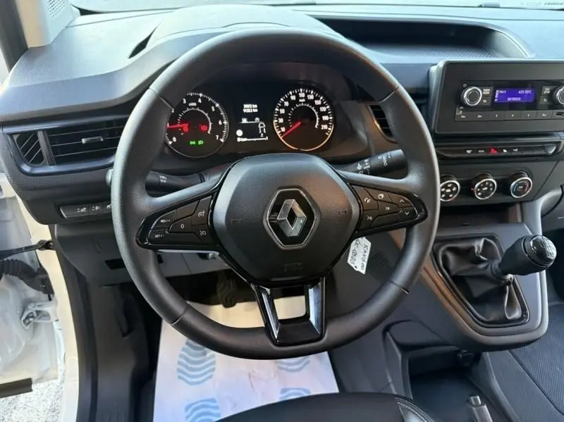 Vue intérieure centrée sur le volant Renault du Kangoo blanc 2022, avec tableau de bord et levier de vitesses manuel visible.