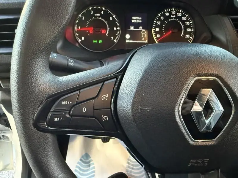 Gros plan sur le volant et le tableau de bord du Renault Kangoo blanc, avec commandes au volant et compteurs visibles.