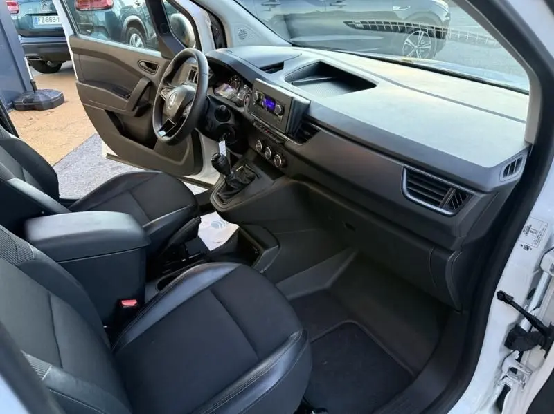 Vue intérieure côté conducteur du Renault Kangoo blanc 2022, avec tableau de bord moderne et boîte manuelle visible.