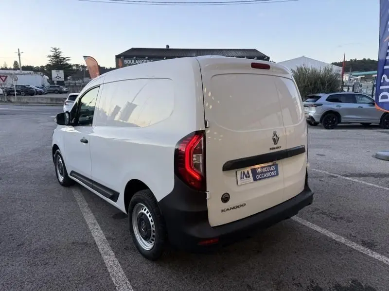 Vue 3/4 arrière droite d’un Renault Kangoo Van blanc, avec feux arrière allumés et logo visible sur porte arrière.