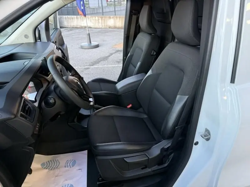 Vue intérieure côté conducteur du Renault Kangoo blanc 2022, mettant en valeur les sièges noirs et le tableau de bord.