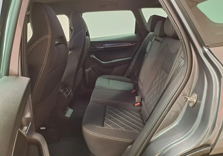 Vue intérieure côté droit sur les sièges arrière en tissu noir avec surpiqûres blanches du Skoda Karoq gris graphite 2025.