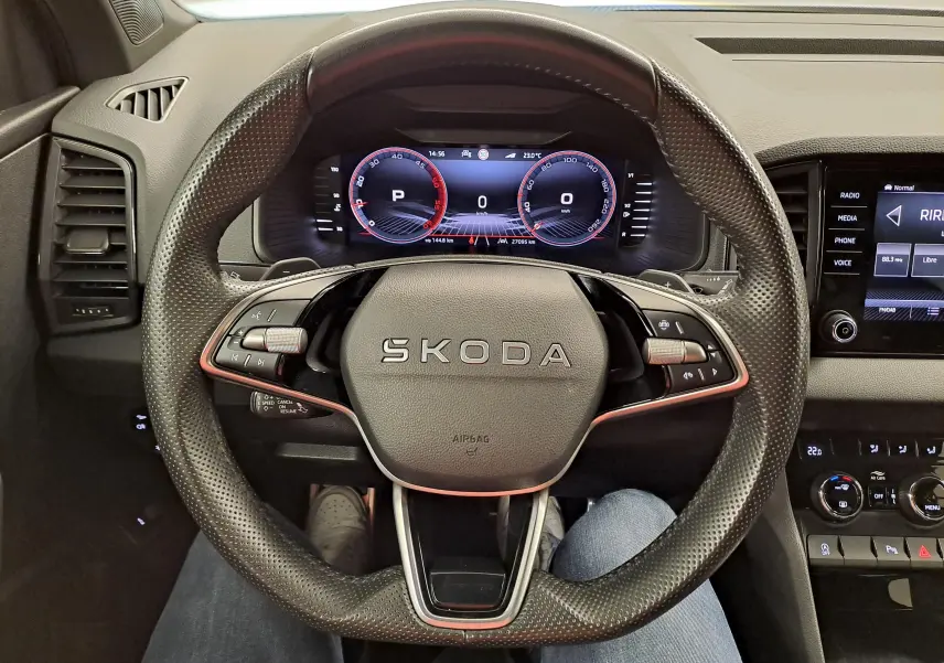 Vue intérieure centrée sur le volant perforé SKODA du Karoq 2.0 TDI 150 DSG7 avec tableau de bord numérique.