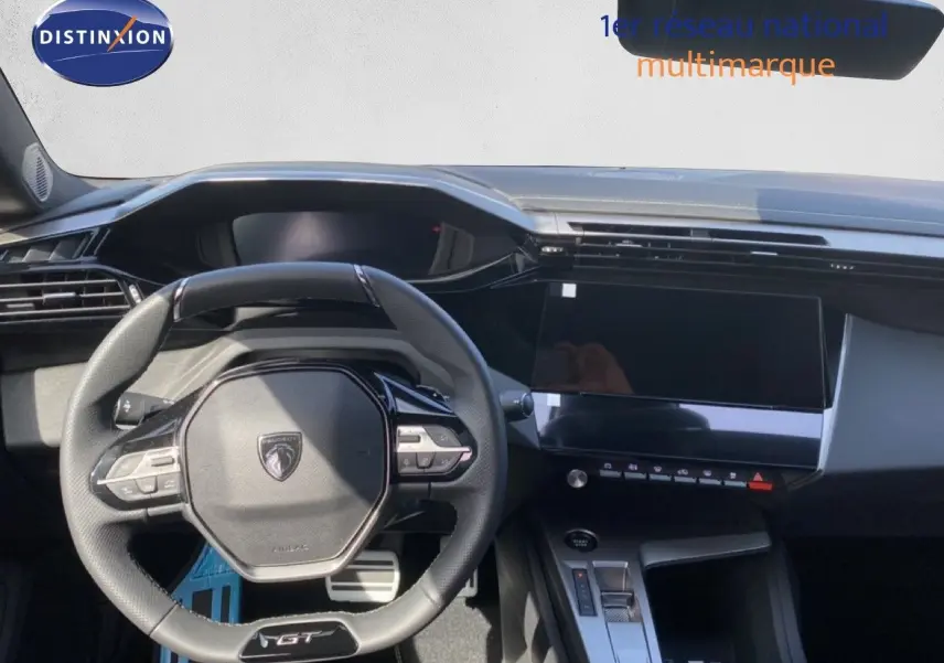 Vue intérieure centrée sur le volant GT et le tableau de bord moderne de la Peugeot 308 Hybrid blanche 2026.