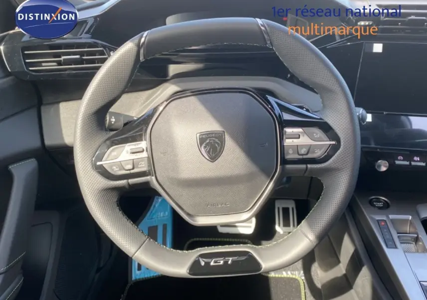Vue rapprochée du volant GT en cuir perforé de la Peugeot 308 Hybrid 145ch, avec commandes intégrées sur un intérieur noir.