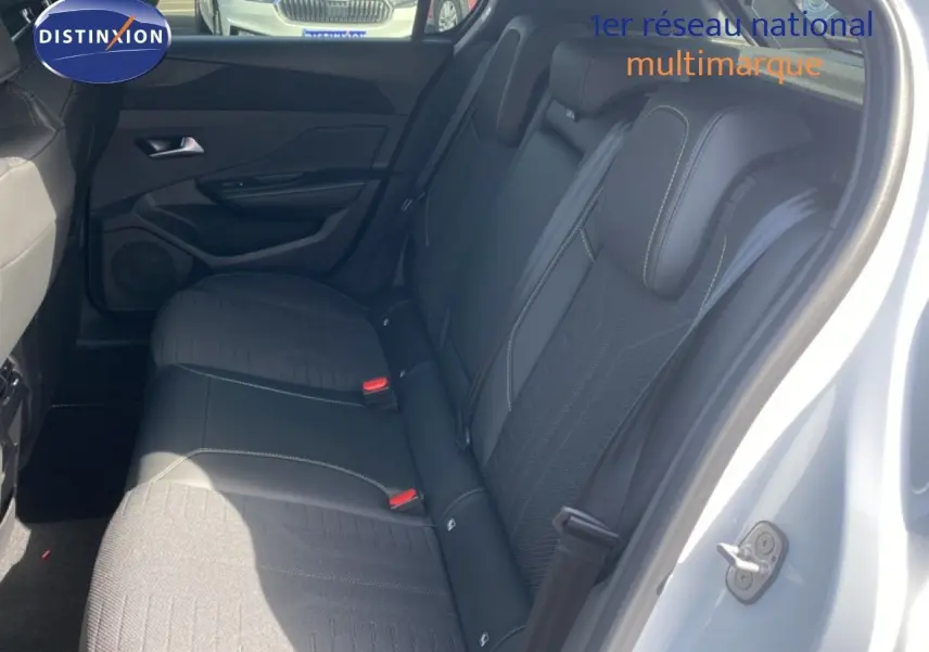 Vue intérieure côté droit montrant la banquette arrière en tissu noir de la Peugeot 308 Hybrid 145ch GT blanche.