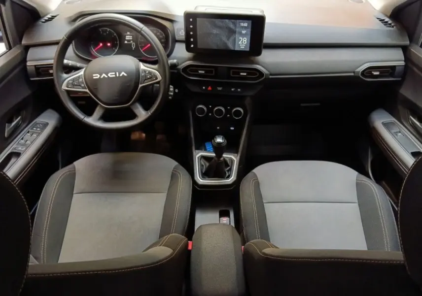Vue intérieure avant de la Dacia Sandero Stepway 2025, tableau de bord avec écran tactile et volant multifonction noir.