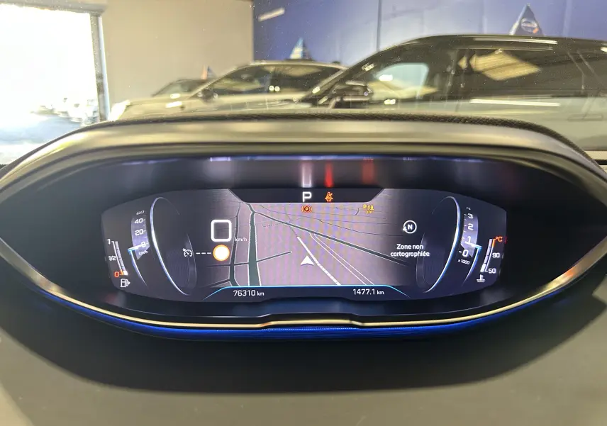 Vue rapprochée du tableau de bord numérique du Peugeot 3008 gris Platinium, affichant la navigation et les compteurs.