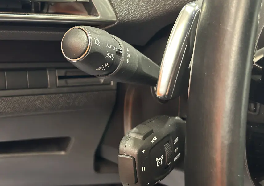 Gros plan sur la commande des phares et régulateur de vitesse du Peugeot 3008 gris Platinium, côté gauche du volant.