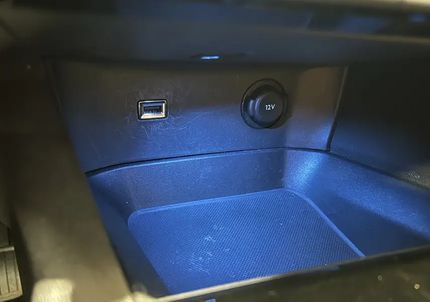 Gros plan sur la prise 12V et port USB dans le compartiment de rangement intérieur d'un Peugeot 3008 gris Platinium.