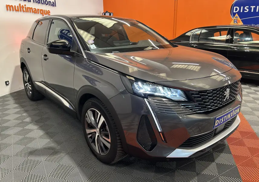 Peugeot 3008 gris Platinium en 3/4 avant droit, avec phares LED allumés et calandre distinctive dans un showroom.
