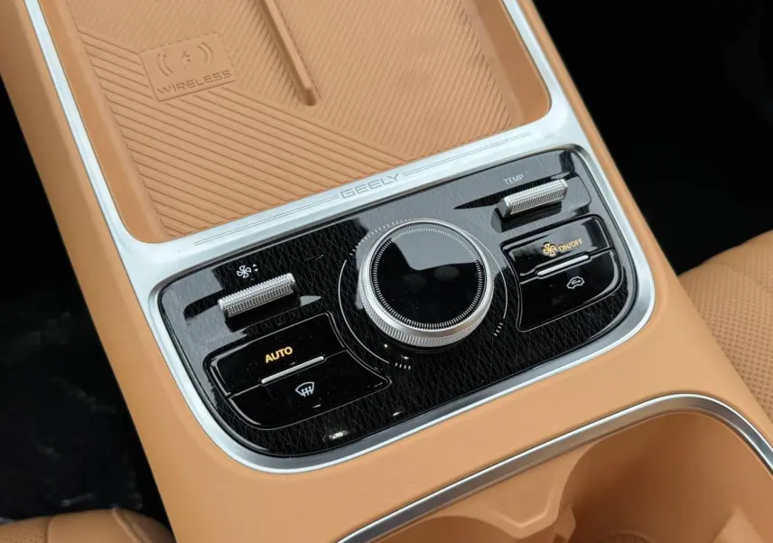 Gros plan sur la console centrale beige du Geely STARRAY 1.5 EM-i avec commandes clim et surface de charge sans fil.