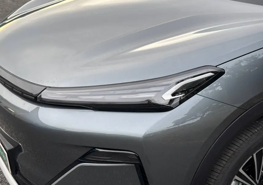 Gros plan sur l'avant droit du Geely STARRAY 1.5 EM-i 262ch Max+ gris Volcanic avec phare LED fin et jante alu visible.