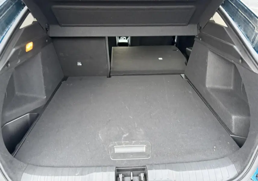 Coffre ouvert du Renault Arkana Bleu Zanzibar, vue de l’arrière avec banquette arrière partiellement rabattue.