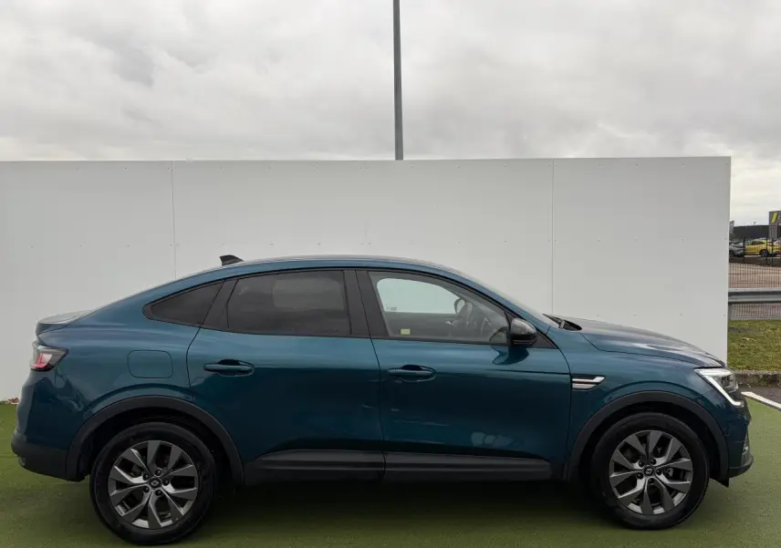 Vue de profil côté gauche d'un Renault Arkana 2025 bleu Zanzibar métal avec vitres surteintées et jantes alliage grises.