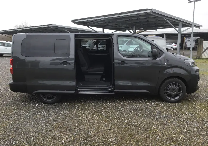 Vue de profil côté droit d’un FIAT Scudo Combi gris titane avec porte coulissante ouverte révélant l’intérieur 9 places.