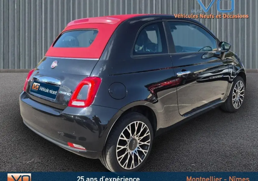 Vue 3/4 arrière droite de la FIAT 500C noire avec toit rouge et jantes alliage 15 pouces, version hybride 2024.