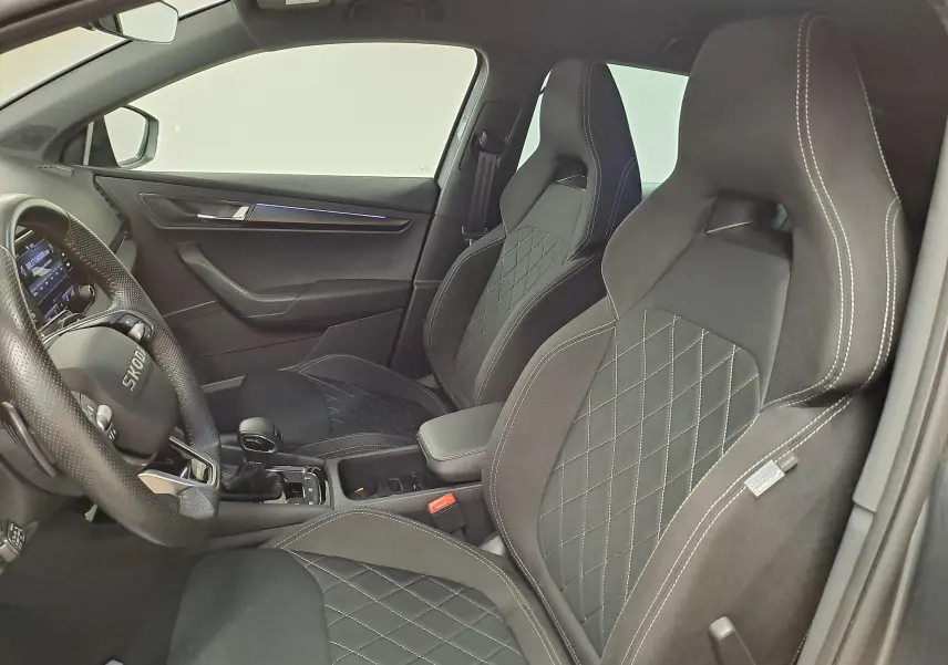Vue intérieure côté conducteur du Skoda Karoq 2.0 TDI 150 DSG7 Sportline avec sièges noirs et volant multifonction.