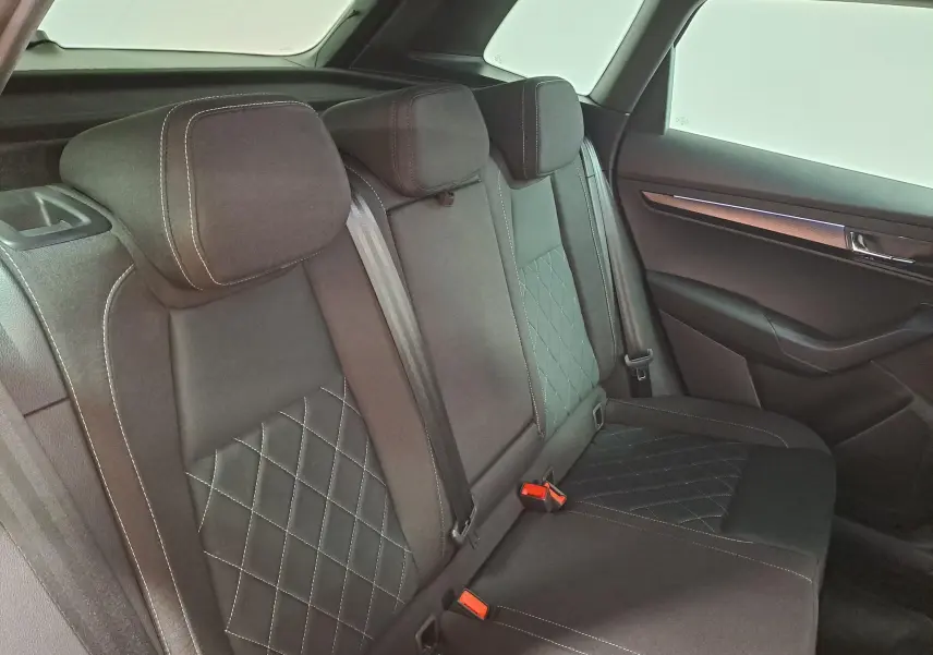 Vue intérieure des sièges arrière noirs avec surpiqûres blanches du Skoda Karoq 2025, côté droit, montrant l'habillage de porte.
