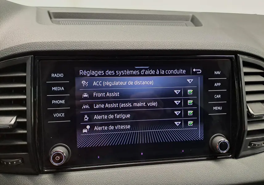 Écran tactile central du Skoda Karoq 2025 affichant les réglages des aides à la conduite, intérieur gris.