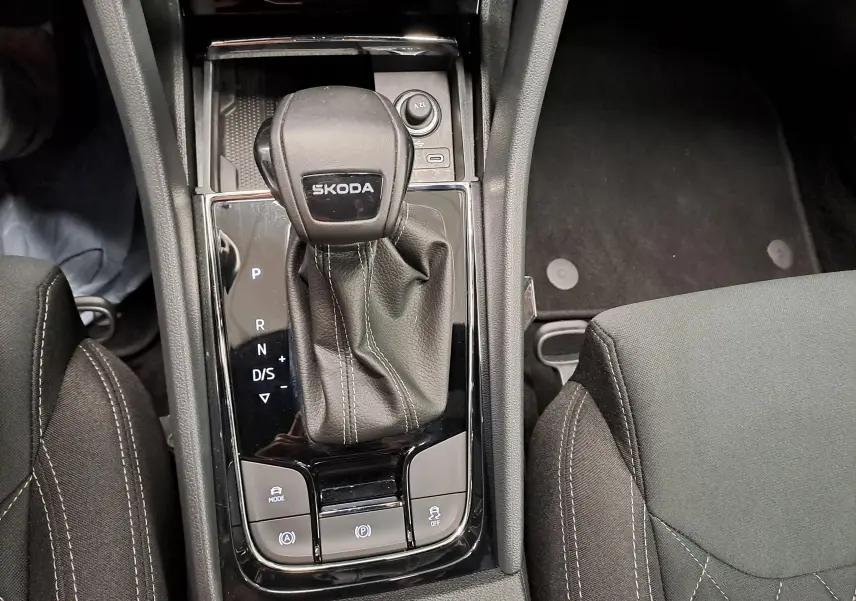 Vue rapprochée de la console centrale avec levier de vitesses automatique SKODA sur finition SPORTLINE, sièges noirs et surpiqûres grises.
