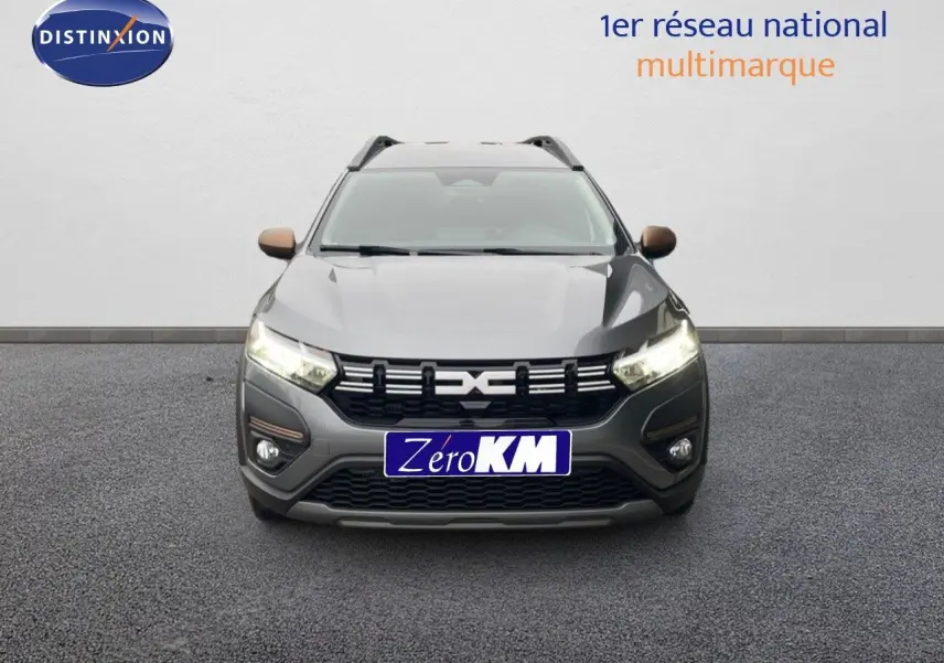 Vue avant d'un Dacia Jogger gris schiste métal avec calandre noire et feux allumés sur fond neutre.