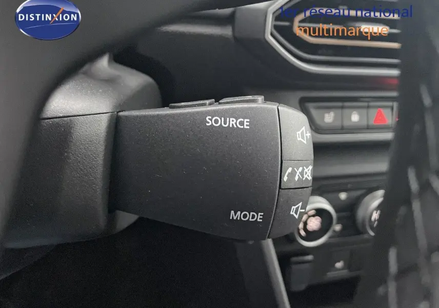 Gros plan sur la commande au volant du Dacia Jogger gris schiste, avec boutons source et mode visibles.