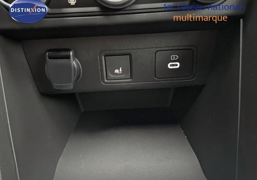 Gros plan sur la console centrale du Dacia Jogger gris schiste, montrant prises USB et bouton d'assistance au stationnement.