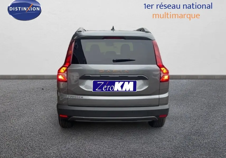 Vue arrière d'un Dacia Jogger gris schiste métal avec feux allumés sur un sol gris uniforme.
