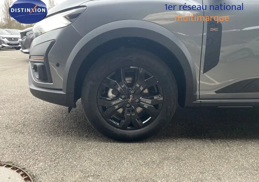 Gros plan sur la roue avant droite d’un Dacia Jogger gris schiste métal avec jante noire et badge Xtreme sur la porte.